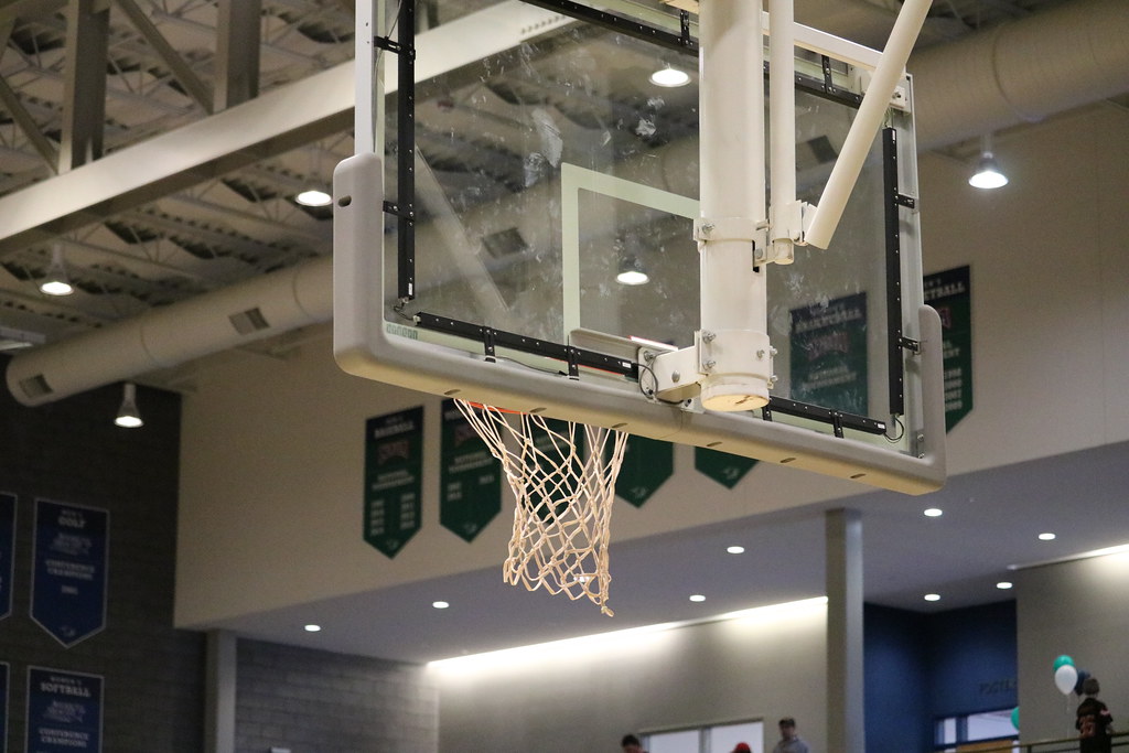 Indoor basketball hoop and backboard inside an arena.
