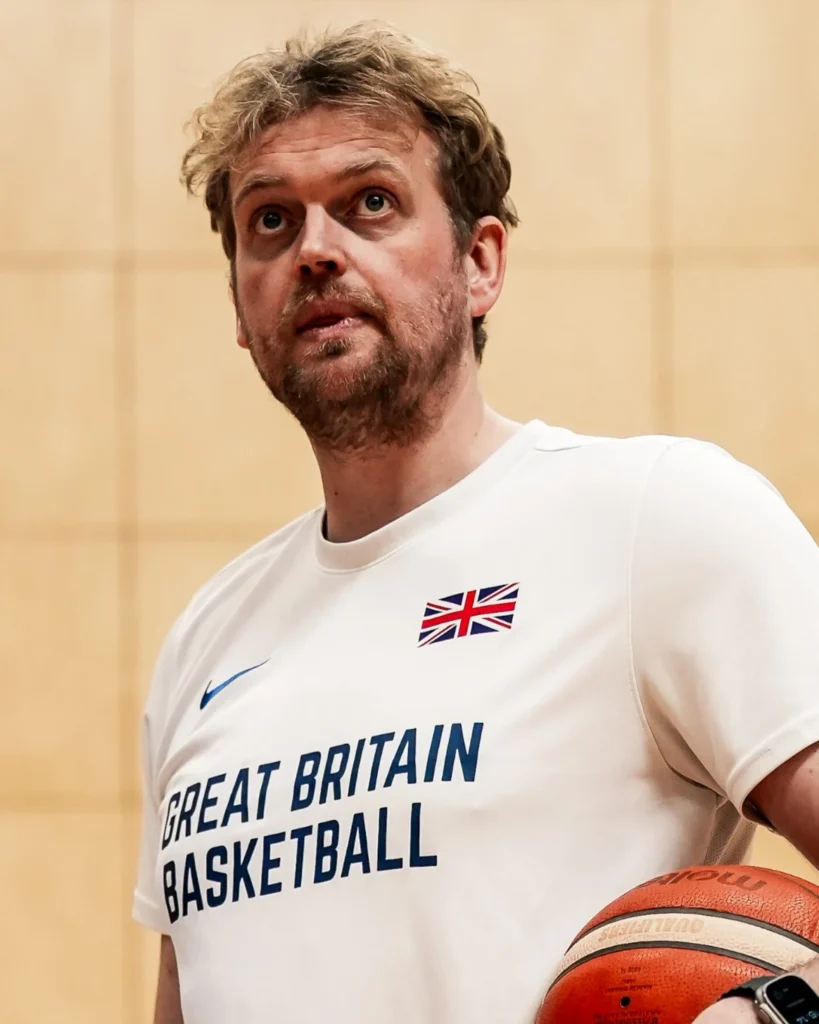 Dan Clark holds a basketball while wearing Great Britain Basketball training kit